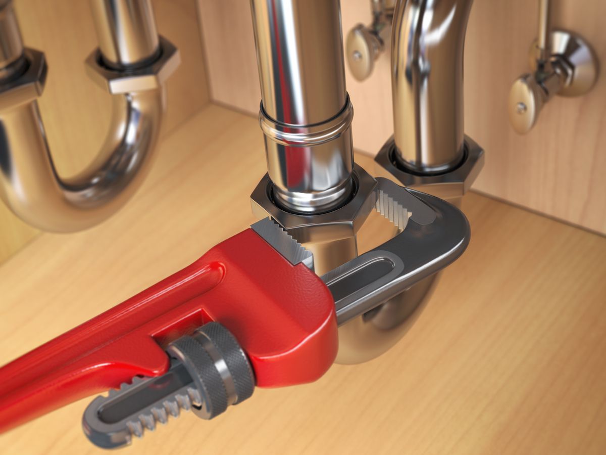 Llave de tubo roja sobre las tuberías cromadas de un fregadero