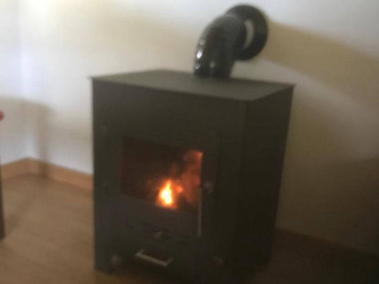 Equipo de chimenea negro encendido con su tubo de salida de humos