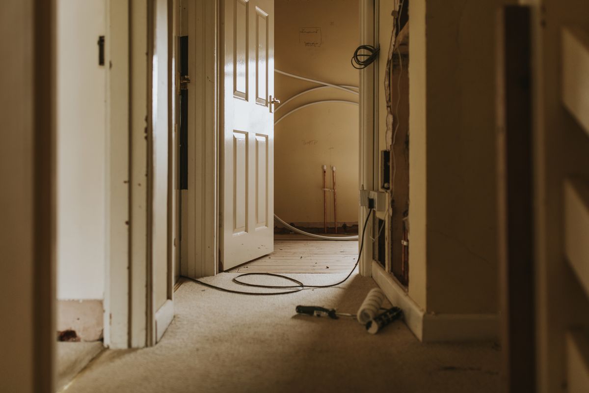 Pasillo de una vivienda en reforma con puertas de madera abiertas y trabajos en curso